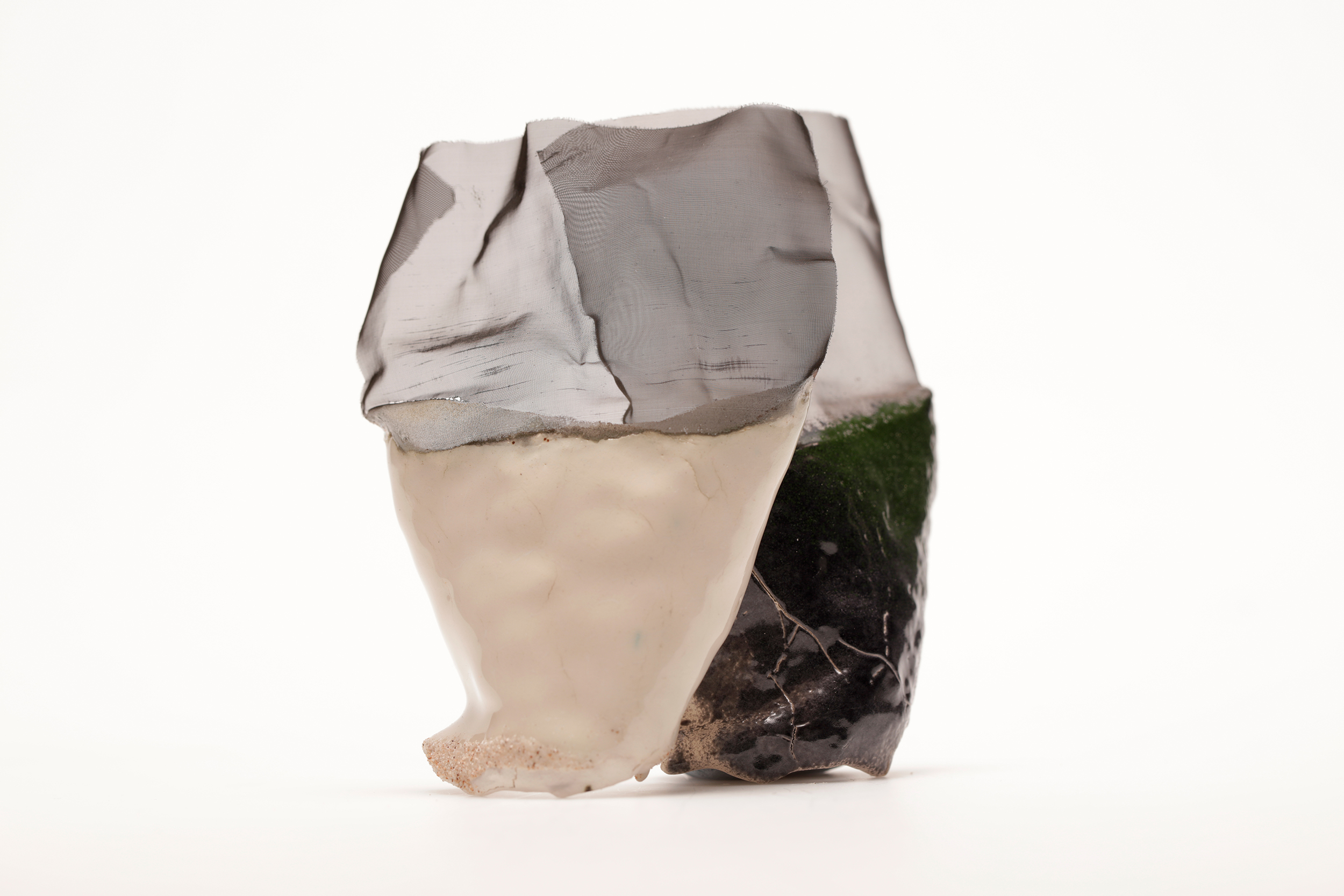 Two objects consisting of ceramic at the bottom and translucent textile at the top, one in front of the other.The two layers of textiles create a darker shade. Against a white background.
